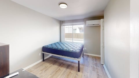 A bedroom with a bed, dresser, and window.